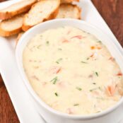 Smoked fish and Dubliner cheese dip in a serving bowl alongside toasted baguette rounds.