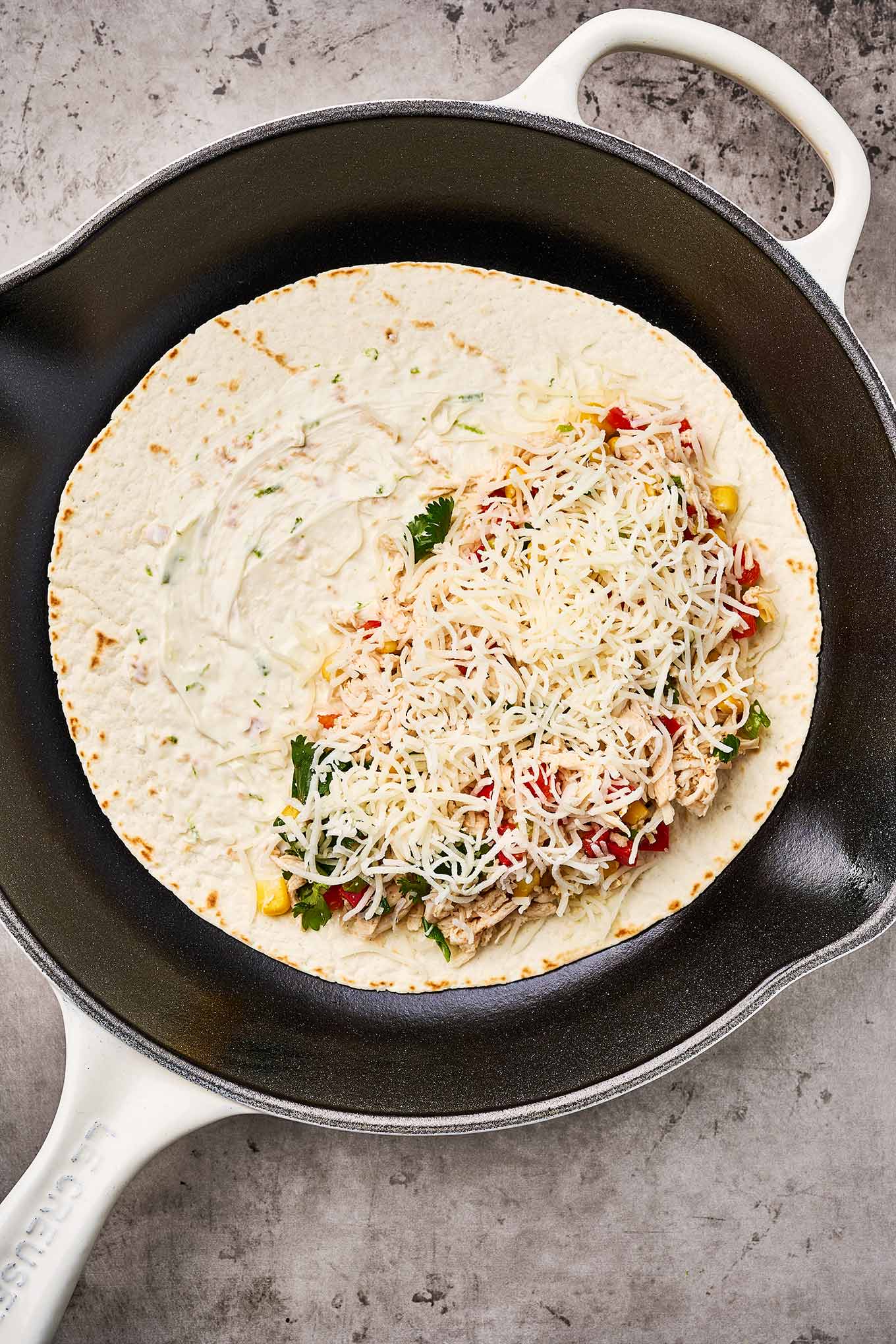 A how-to-make chicken quesadillas photo showing how to add the filling to the tortilla for easy turning during cooking.