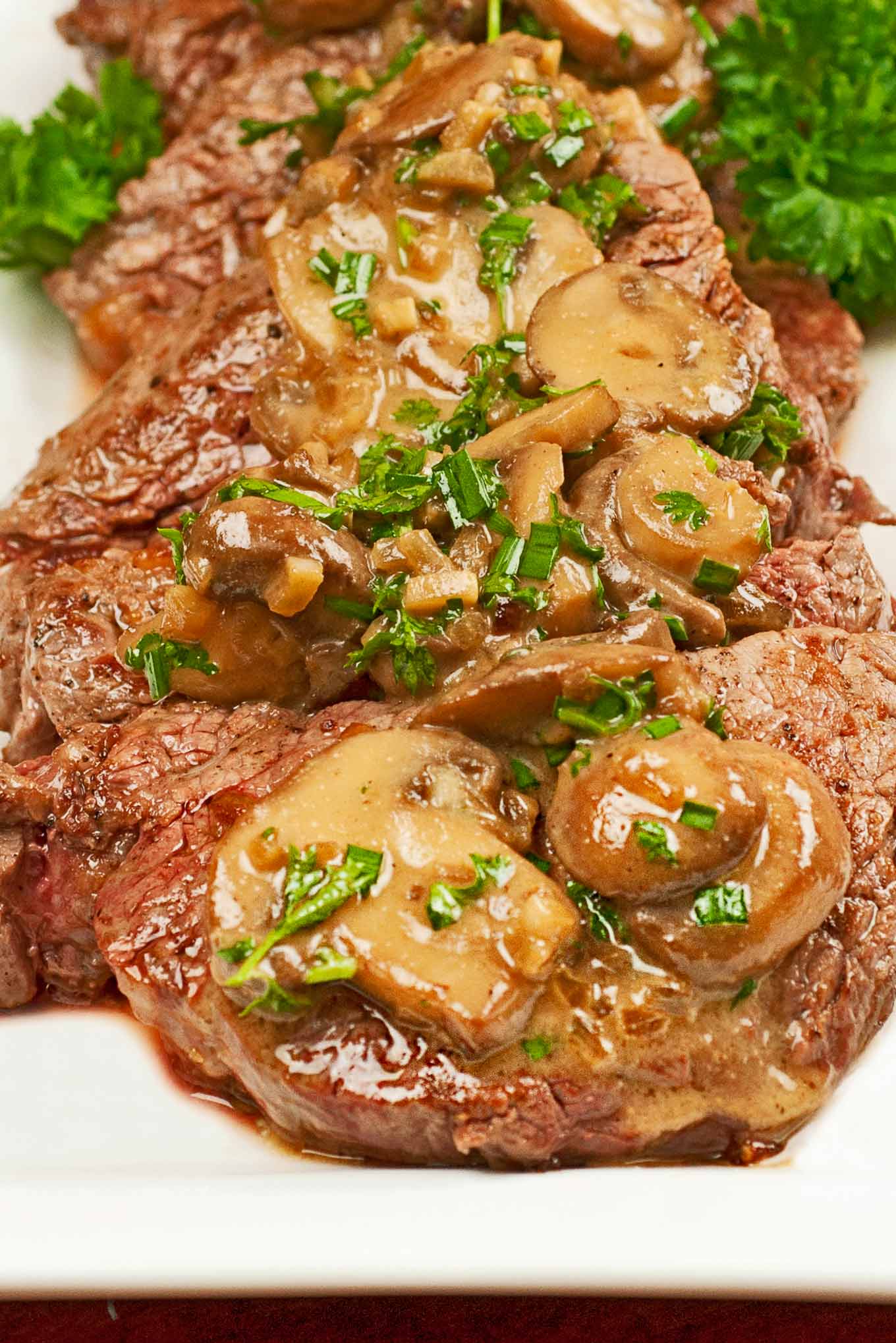 A serving platter of medallions of beef tenderloin topped with sautéed mushrooms and a brandy cream sauce.