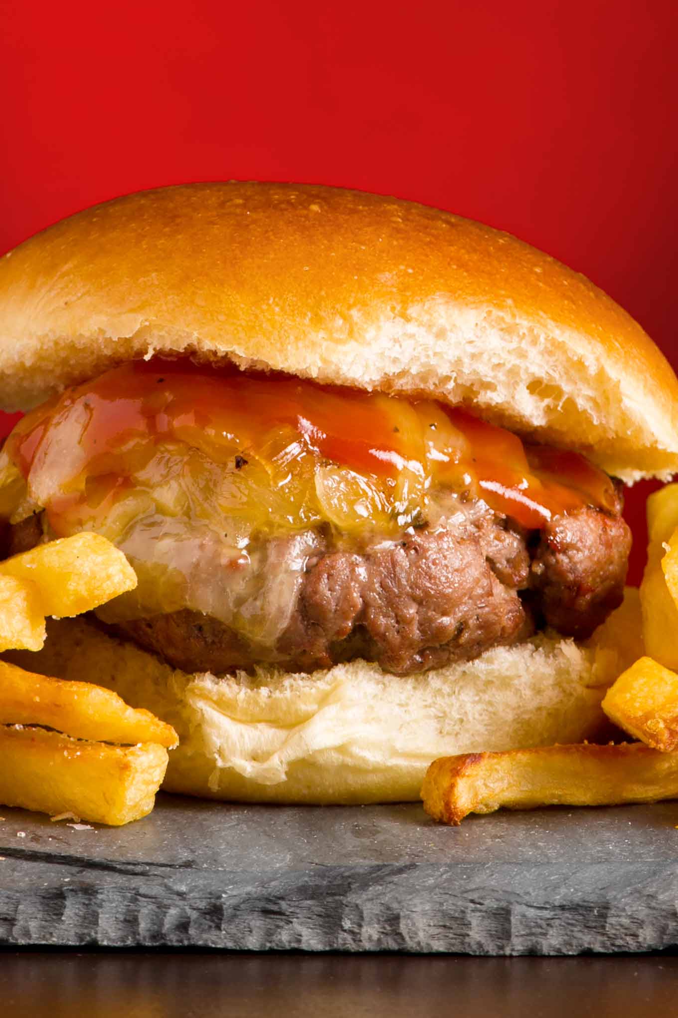 Grilled burger topped with onions, Vermont cheddar cheese, and maple ketchup.