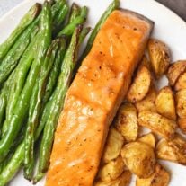 A single serving of sheet pan salmon dinner including brown sugar-glazed salmon, roasted baby potatoes, and green beans.