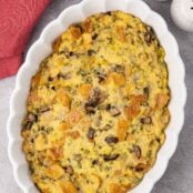 An oval casserole dish filled with old-fashioned bread stuffing made with sourdough bread, celery, onions, and mushrooms.