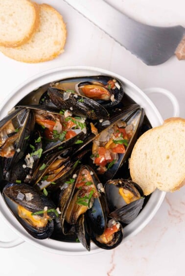 Crock filled with steamed mussels topped with saut&eacute;ed onion, garlic, diced tomatoes, and parsley.