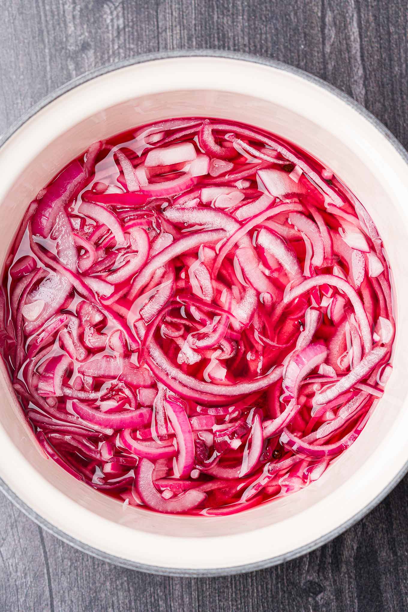 Sliced red onions in a saucepan with pickling brine. 