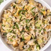 Serving bowl filled with snail (scungilli) salad with celery, onion, parsley, and crushed red pepper.