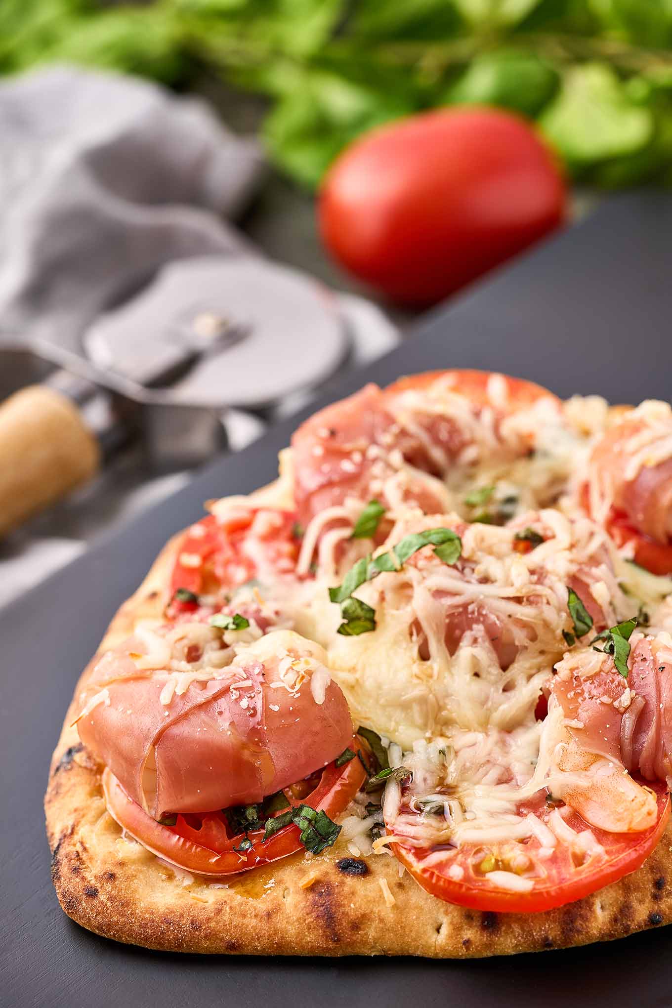 Crispy naan pizza topped with prosciutto-wrapped jumbo shrimp, sliced tomato, fresh basil, and melted mozzarella.