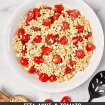 A bowl of pearl couscous combined with grape tomatoes, feta cheese and fresh mint.