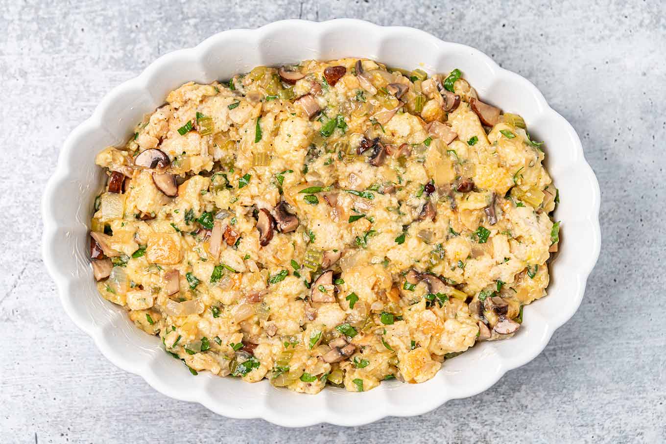 An oval white casserole of old fashioned bread stuffing ready to be baked.