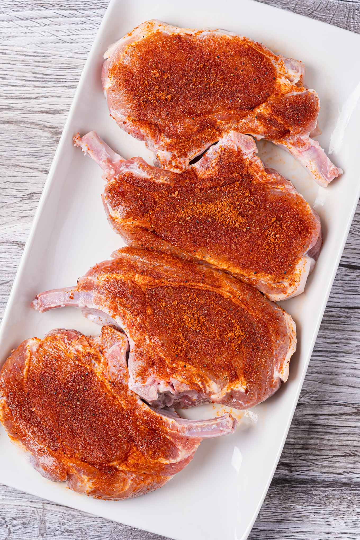 Bone-in pork rib chops coated with BBQ spice rub to illustrate proper application.