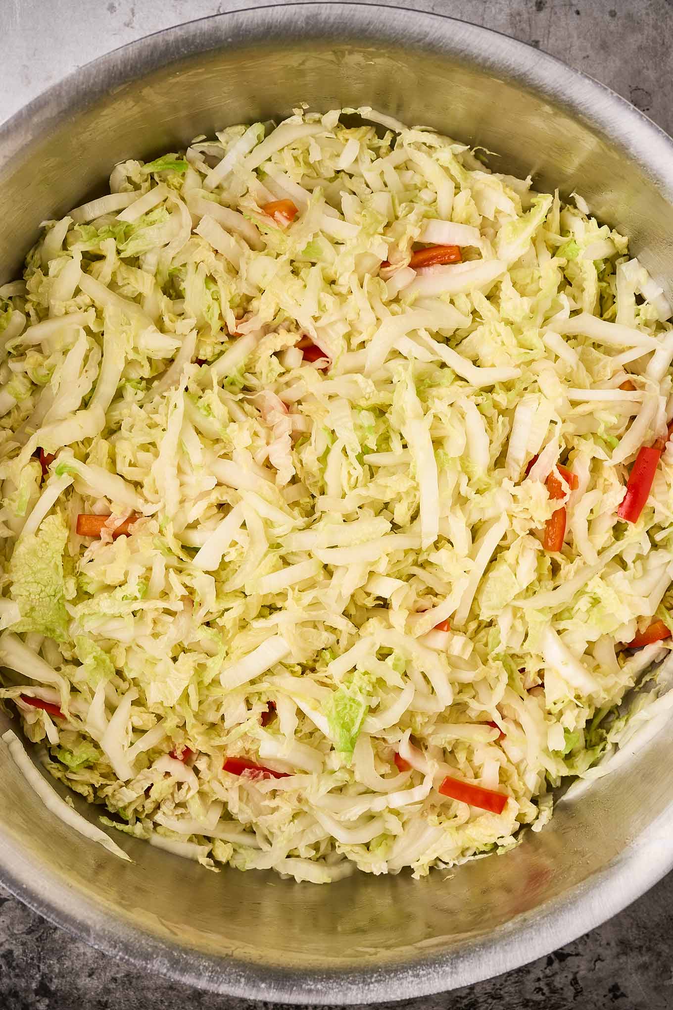 A soup pot filled with stir-fried napa cabbage and red bell peppers.