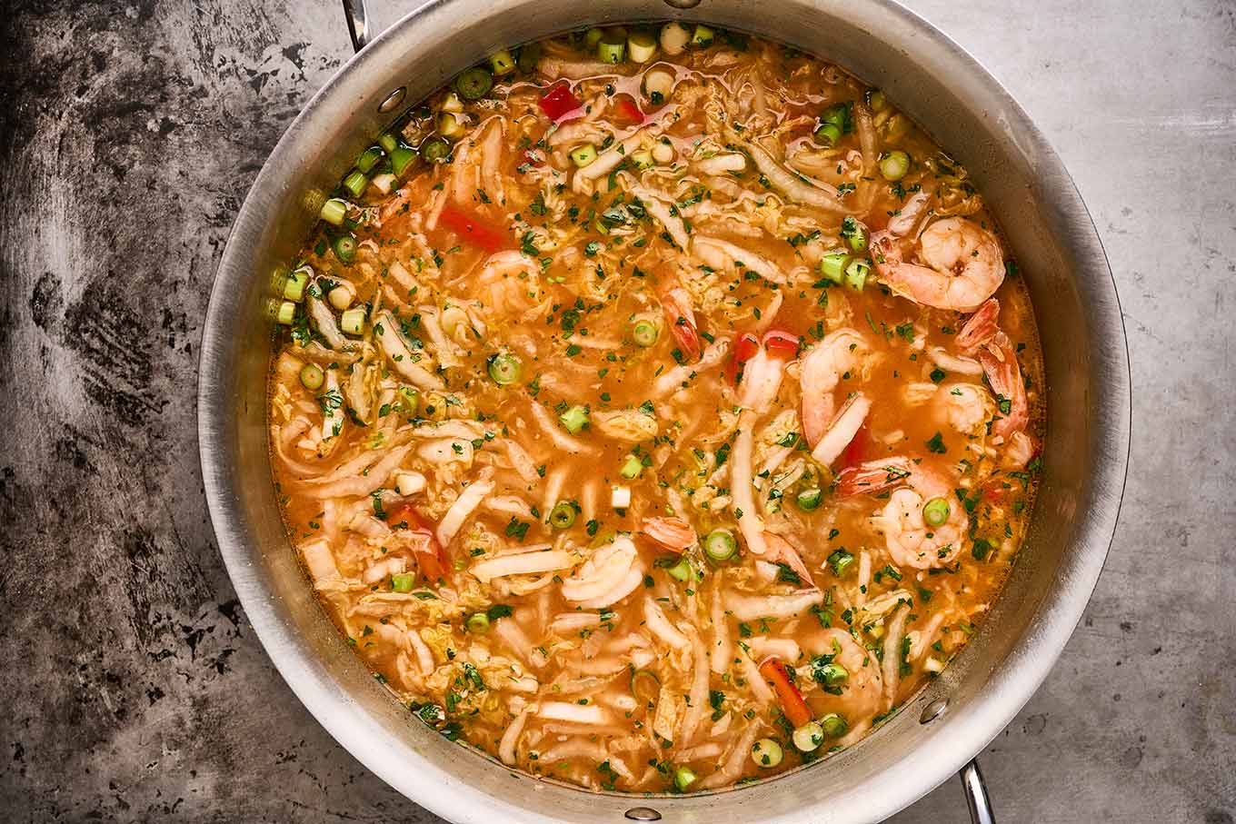 An overhead view of finished shrimp ramen noodle soup in a soup pot, ready to be served.