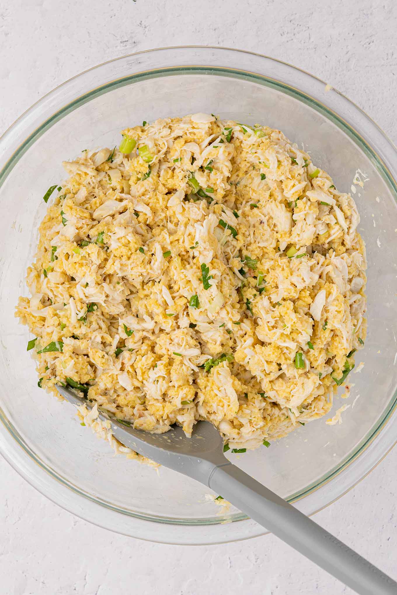 A mixing bowl filled with crab mixture ready to be formed into crab cakes.