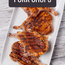 An overhead view of a white oblong serving platter with four brined and grilled pork chops.