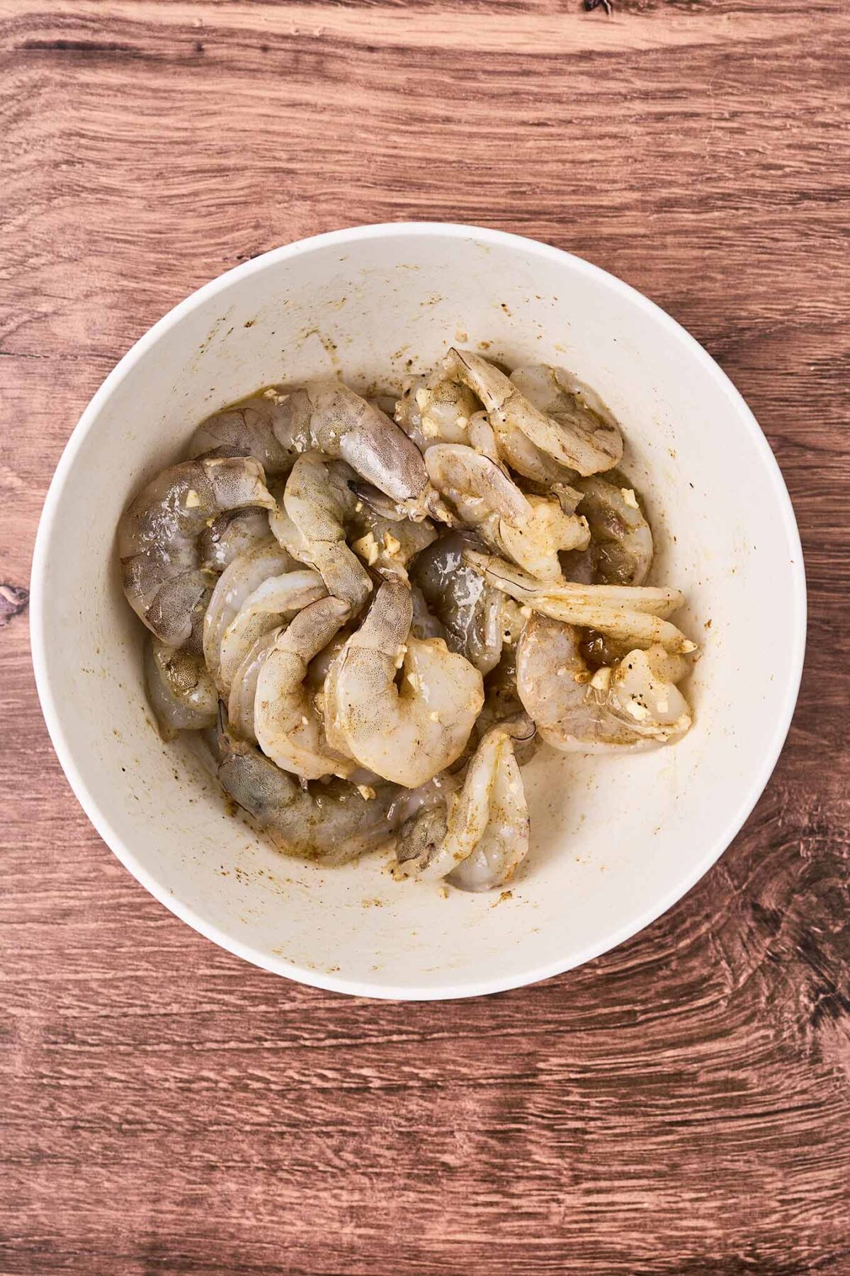 Shrimp being marinated in olive oil, lime juice, garlic, and cumin before being sautéed for shrimp roll sandwiches.