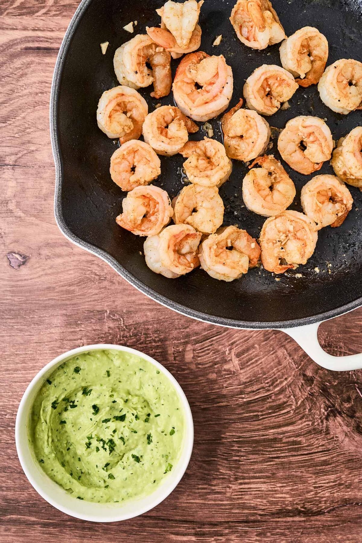 Shrimp rolls with avocado mayo being prepared; sautéed shrimp in a cast iron pan and a dish of avocado cilantro mayonnaise to the side.