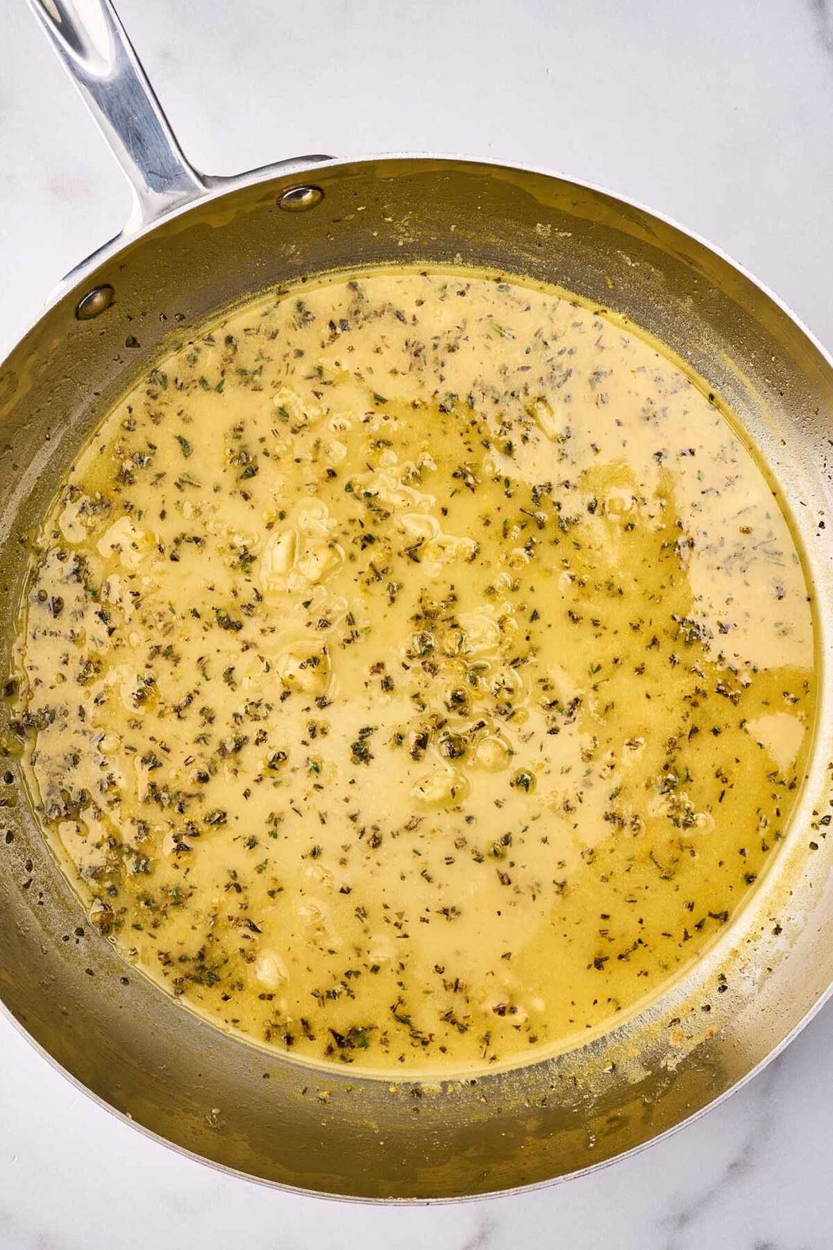 A frying pan with Sicilian style citrus sauce for the pasta; olive oil, fresh herbs, garlic, lemon juice, orange juice, and orange zest.
