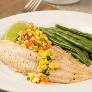 Easy fish recipes; broiled catfish fillet with fresh corn salsa on a plate with steamed green beans.