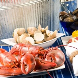 All seafood recipes; a stovetop clambake with boiled lobsters on a platter, a bowl of steamed clams, and a bowl of mussels.