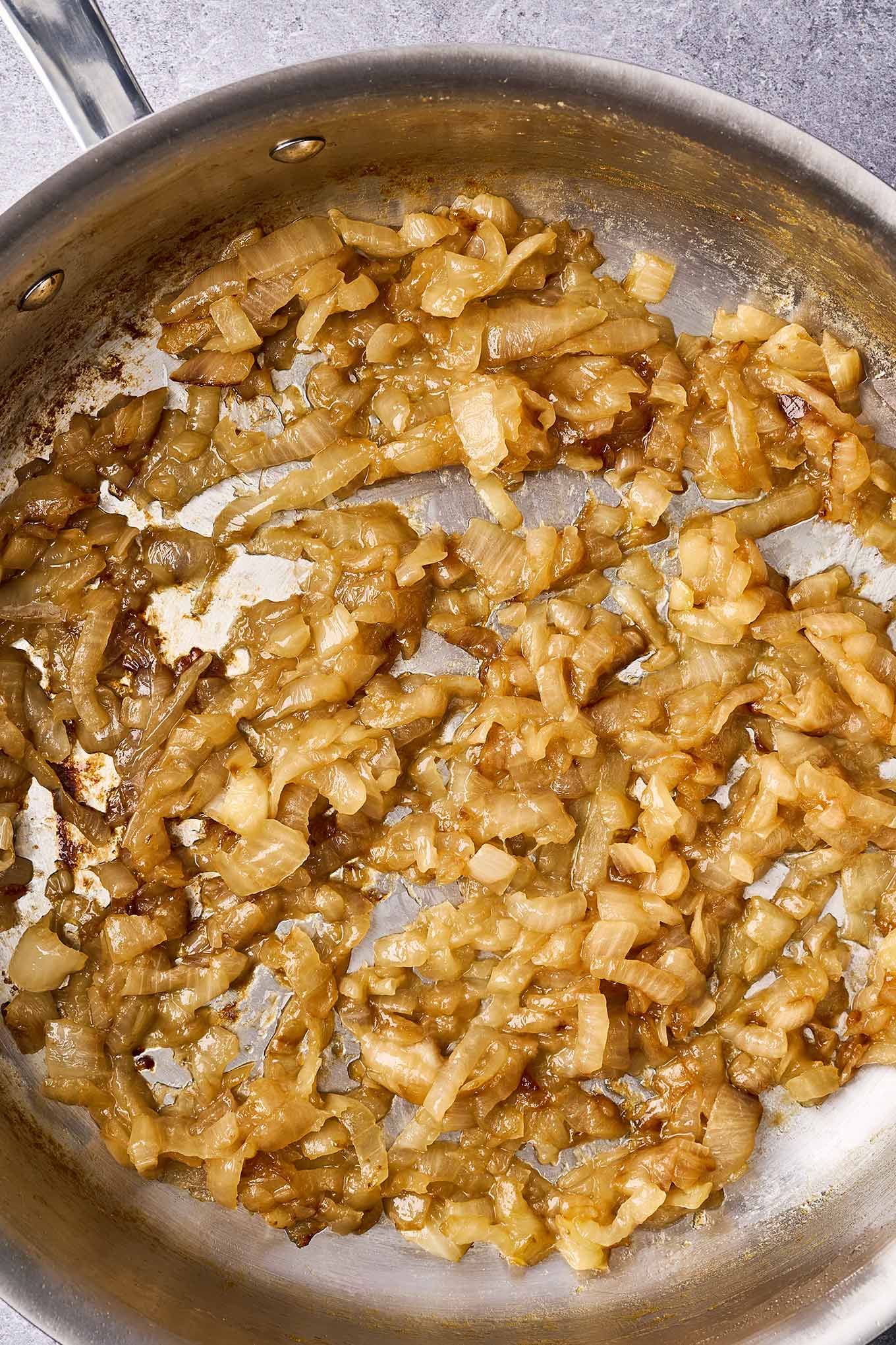 A stainless steel skillet filled with perfectly caramelized onions.