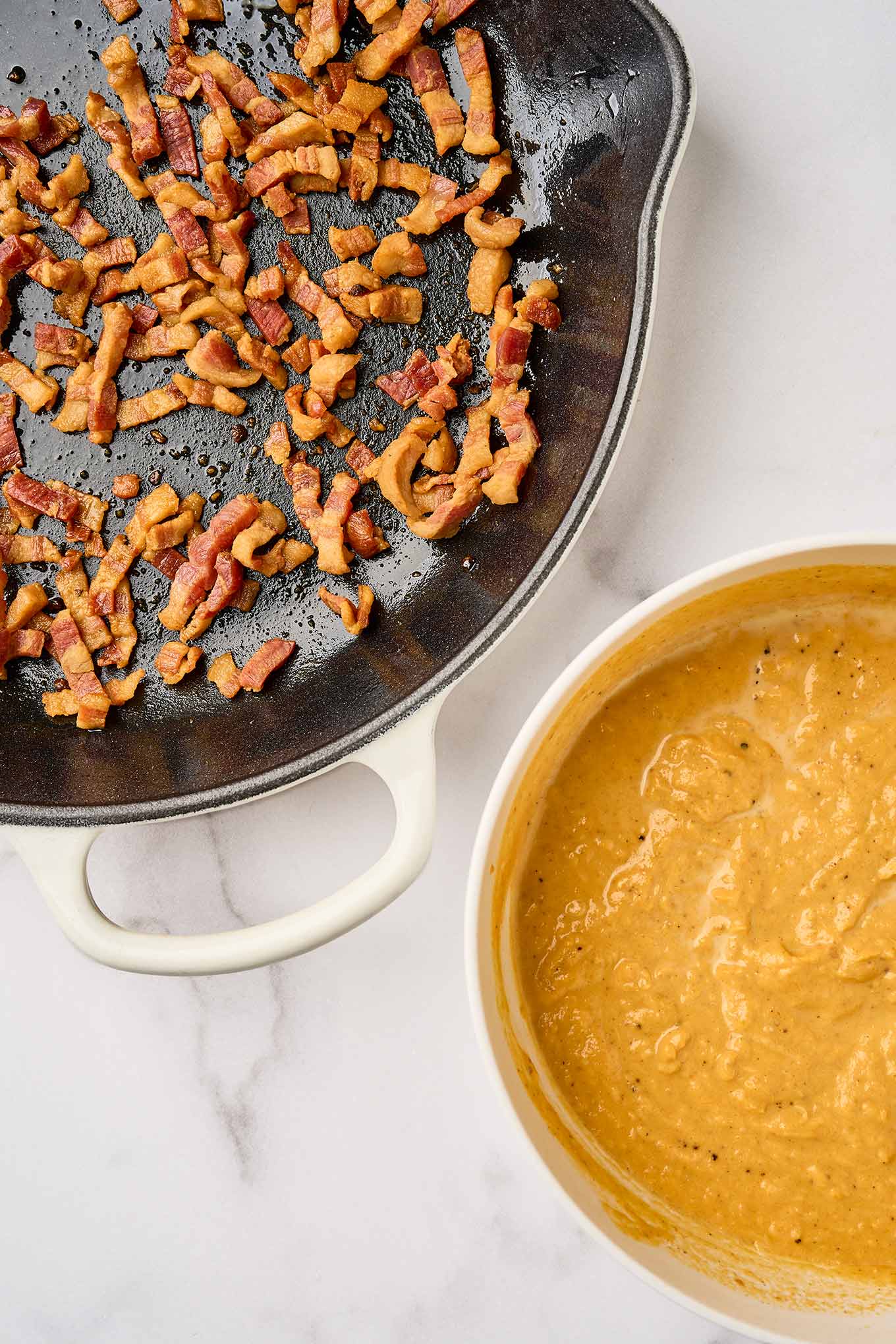 First steps in making creamy pumpkin pasta; crispy fried pancetta in a cast iron skillet, pumpkin puree, half-and-half, and nutmeg in a mixing bowl.