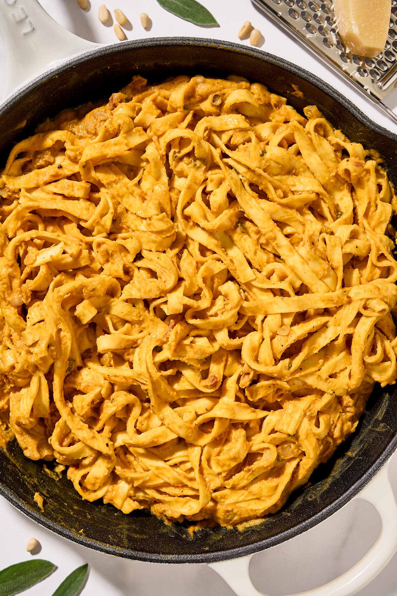 The last step for preparing creamy pumpkin pasta, fettuccine combined with pumpkin puree, pancetta, pine nuts, sage, and half and half.