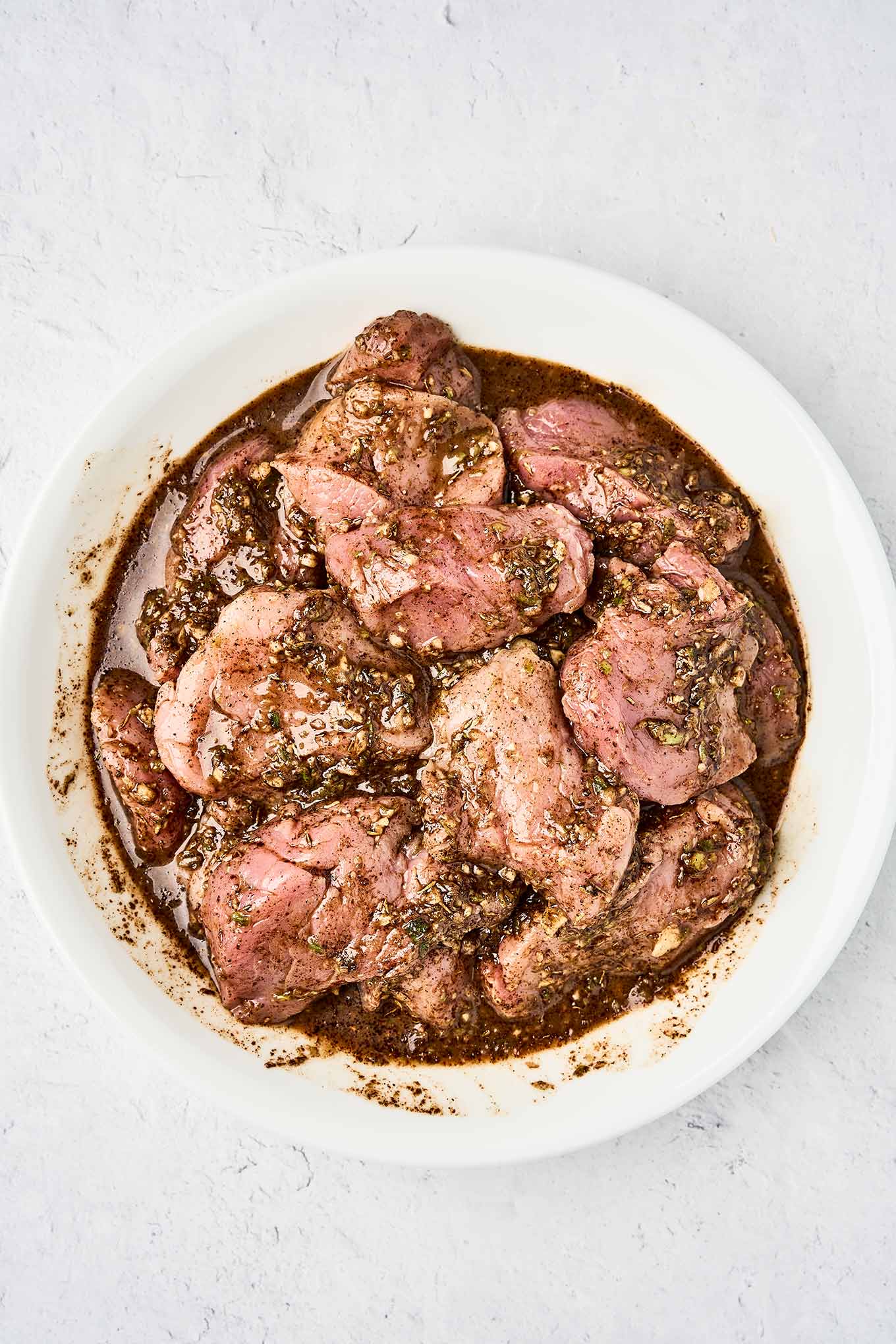 Pork tenderloin medallions coated in jerk marinade prior to cooking.