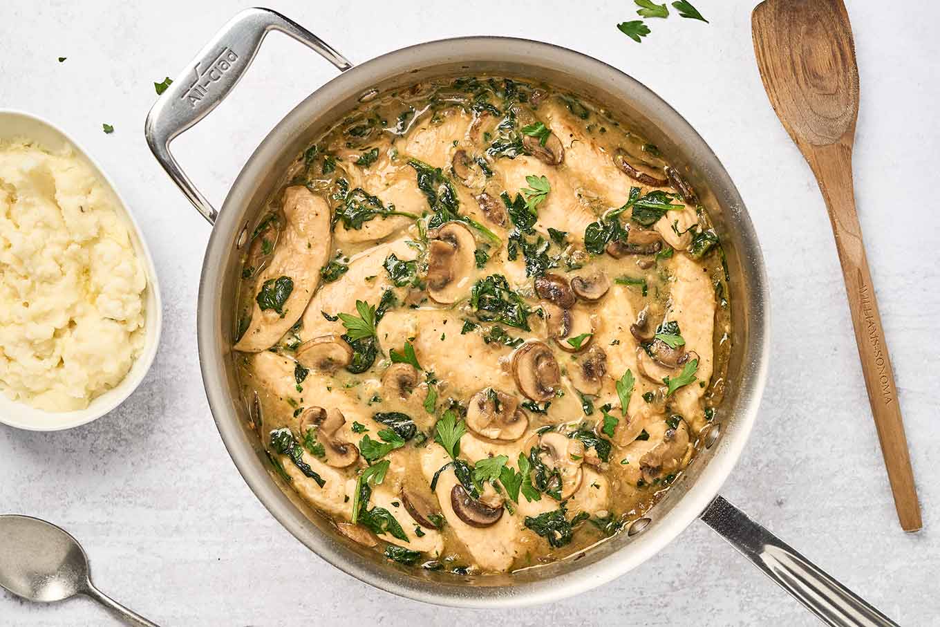 Mushroom chicken with spinach in a creamy, cheesy sauce, cooked in one pan and served with mashed potatoes.