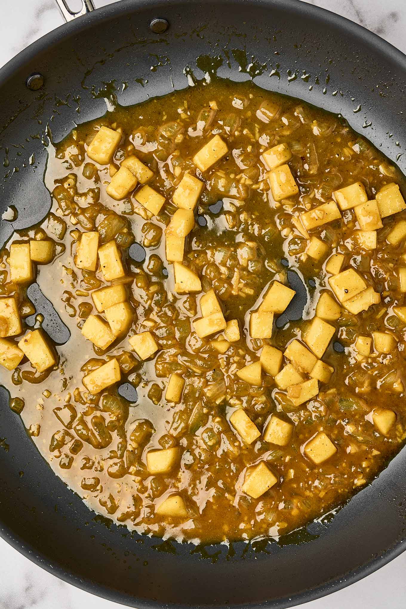 Preparing the creamy curry sauce with sautéed onions, garlic, chunks of apple, and apple cider.