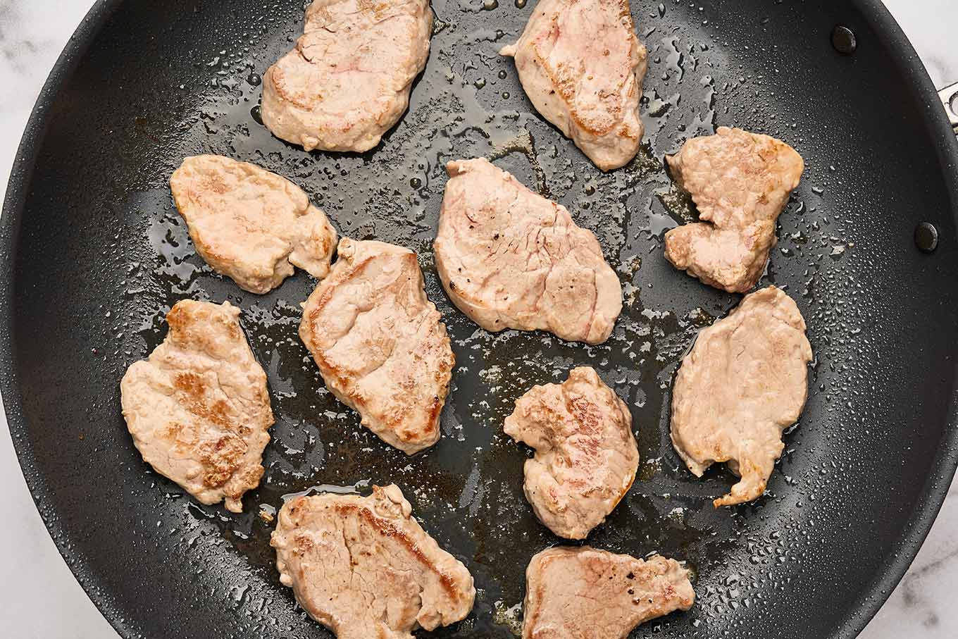 The first step to making pork tenderloin sliders is to quickly sear the medallions on both sides until lightly browned.