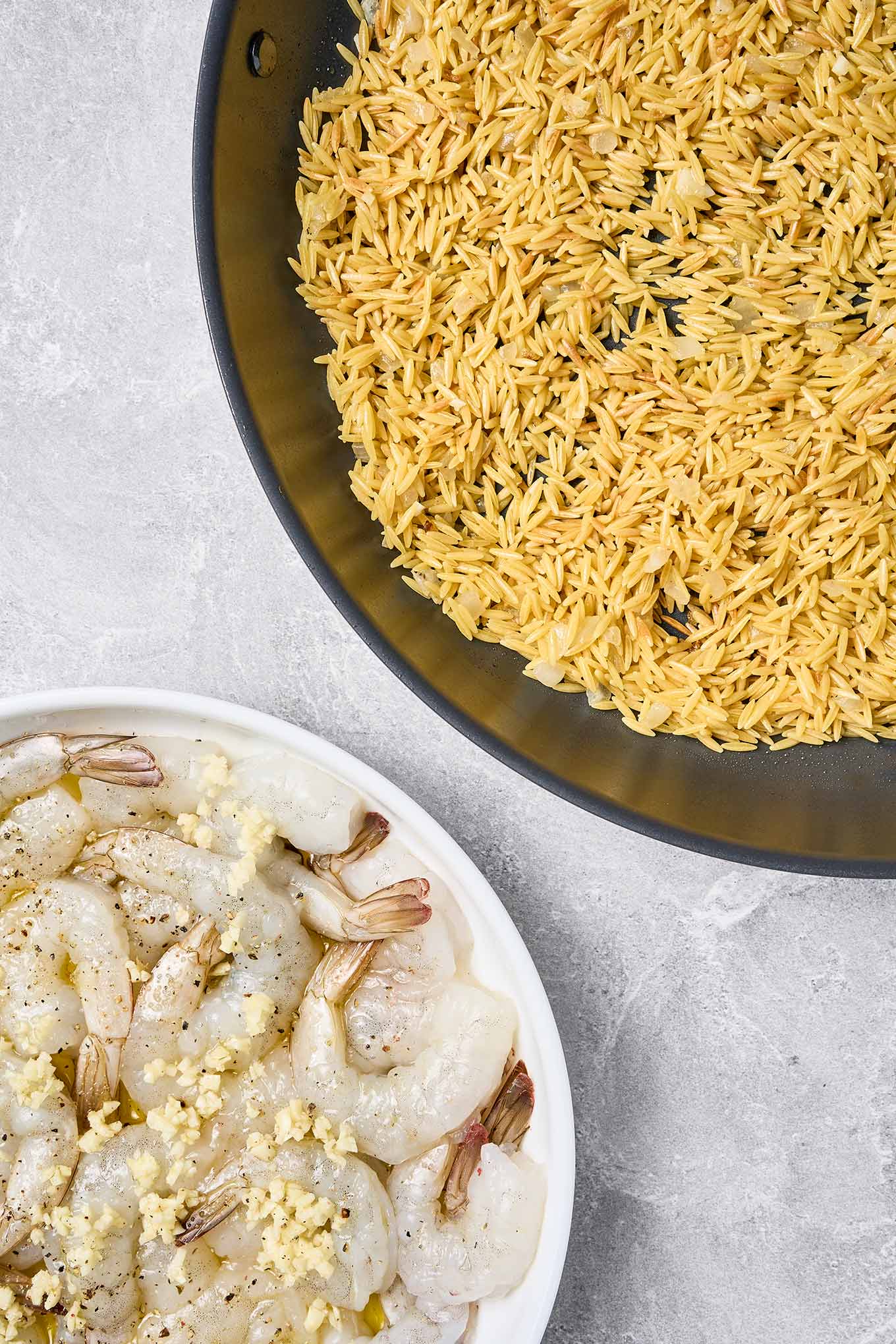 Step one of shrimp scampi with orzo: toasting orzo for flavor and marinating raw shrimp in garlic and olive oil.