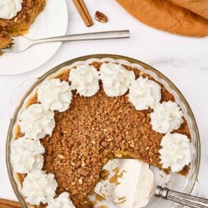Crustless pumpkin pie with pecan gingersnap streusel and whipped cream, one slice served on a plate.