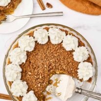 Crustless pumpkin pie with pecan gingersnap streusel and whipped cream, one slice served on a plate.