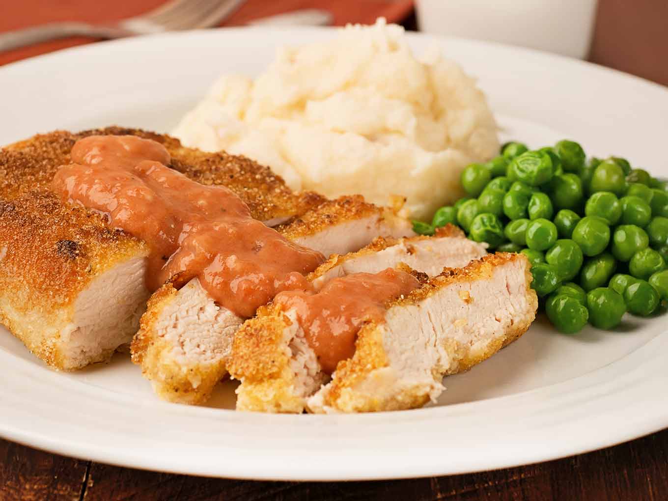 Sliced, cornmeal crusted chicken, pan-fried and served with Southern tomato gravy, mashed potatoes, and green peas.