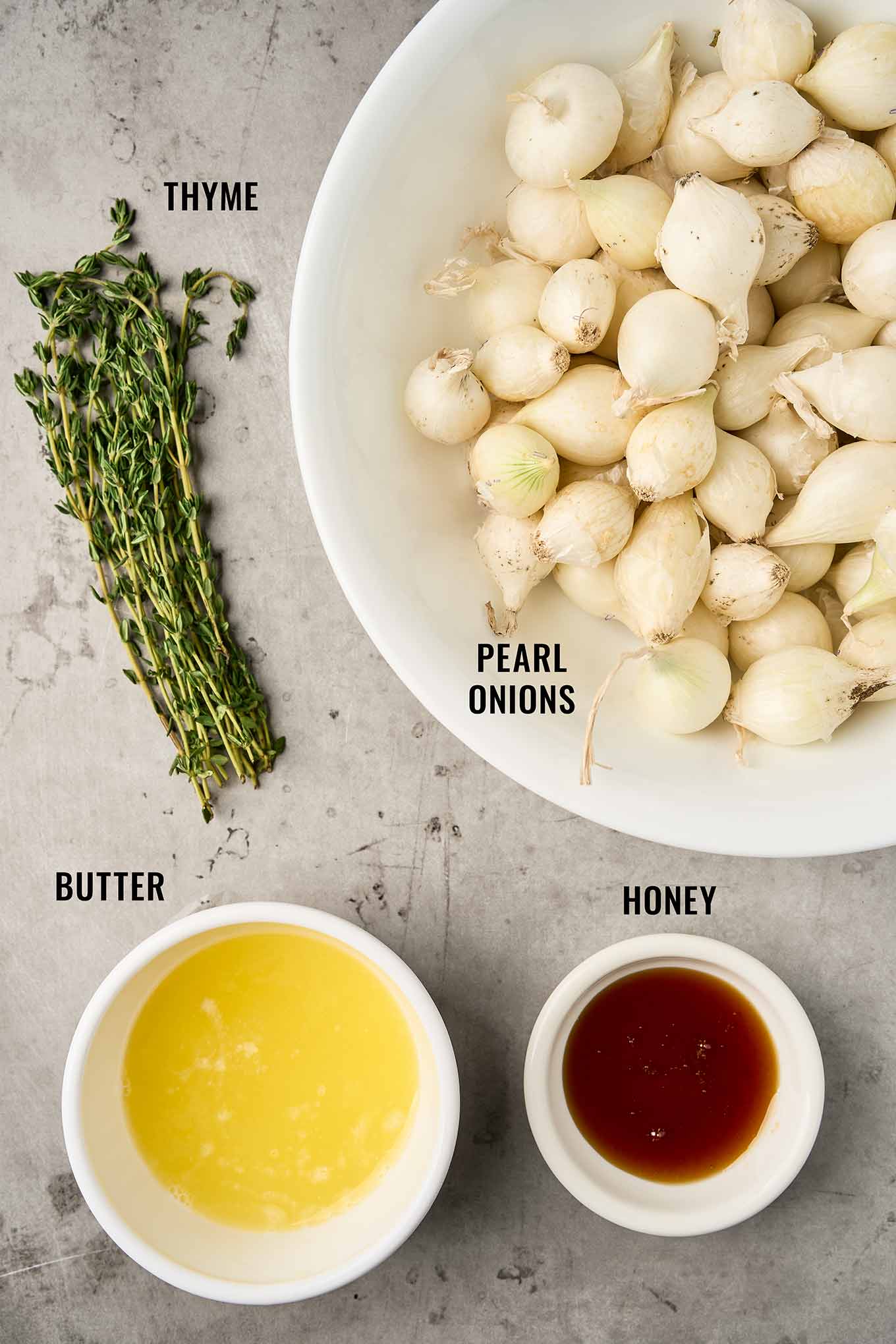 Ingredients for roasted pearl onions including pearl onions, fresh thyme, melted butter, and honey.