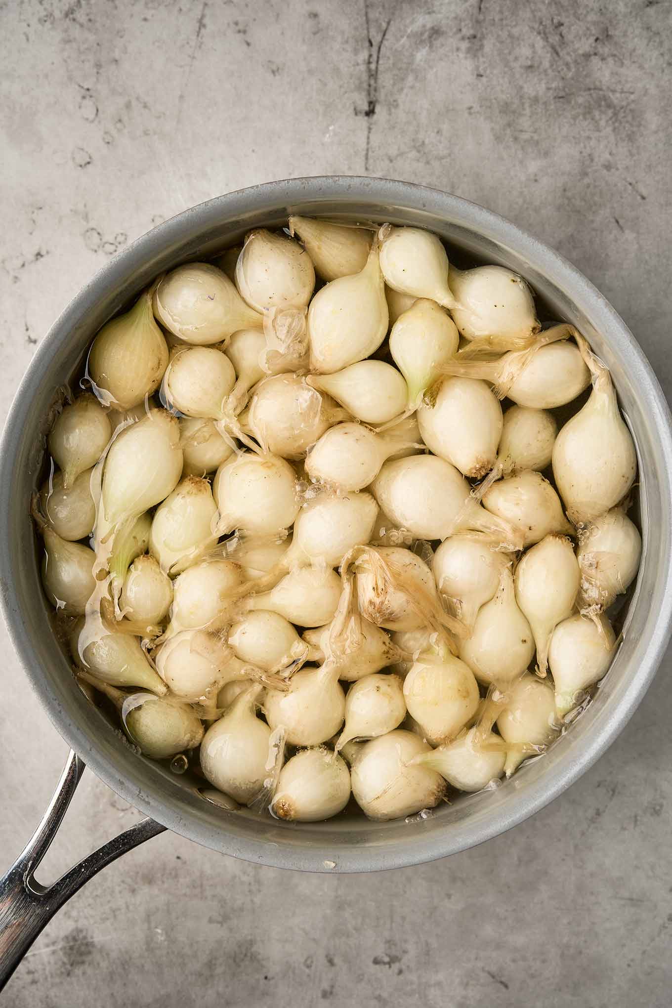 Pearl onions simmering in boiling water to loosen their skins.