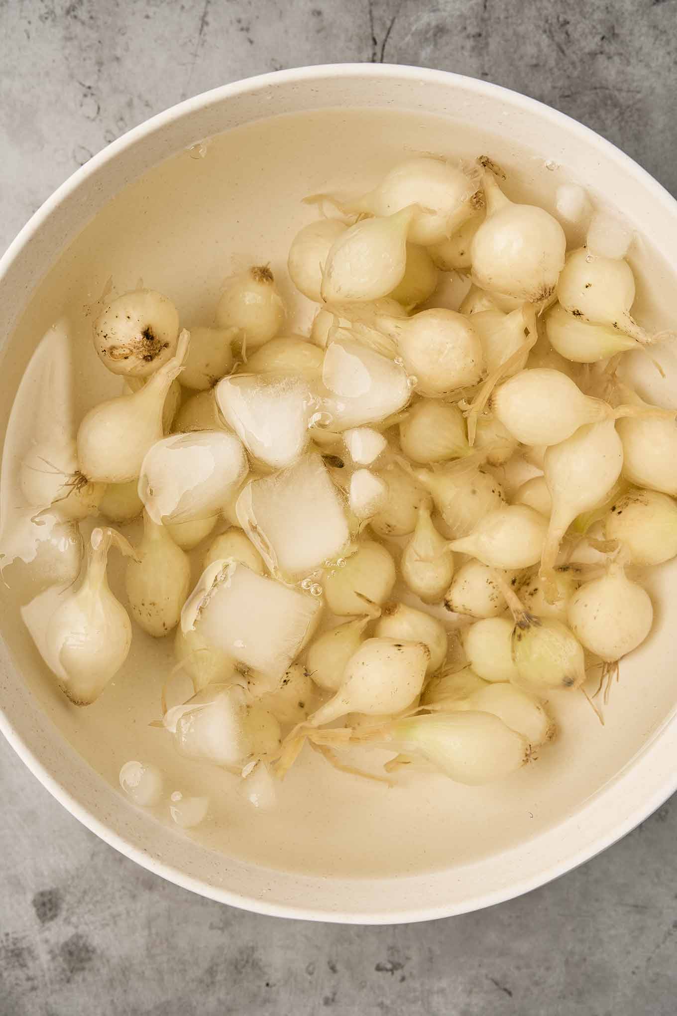 Pearl onions cooling in an ice bath after boiling to loosen their skins.