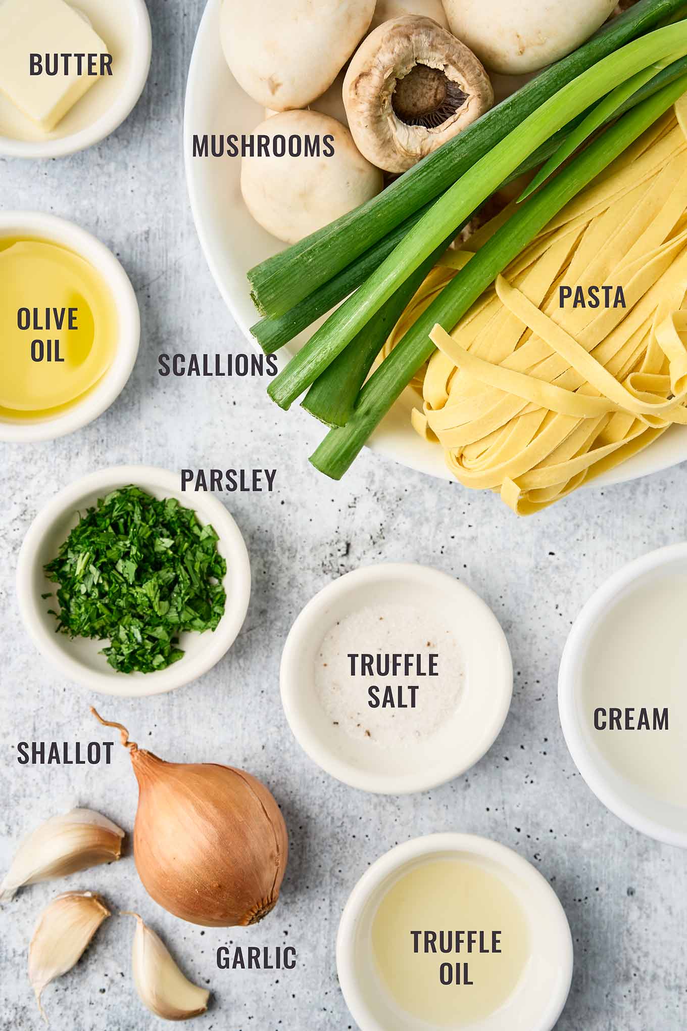 Ingredients for truffle mushroom pasta including mushrooms, pasta, scallions, parsley, garlic, shallot, cream, butter, olive oil, truffle oil, and truffle salt.