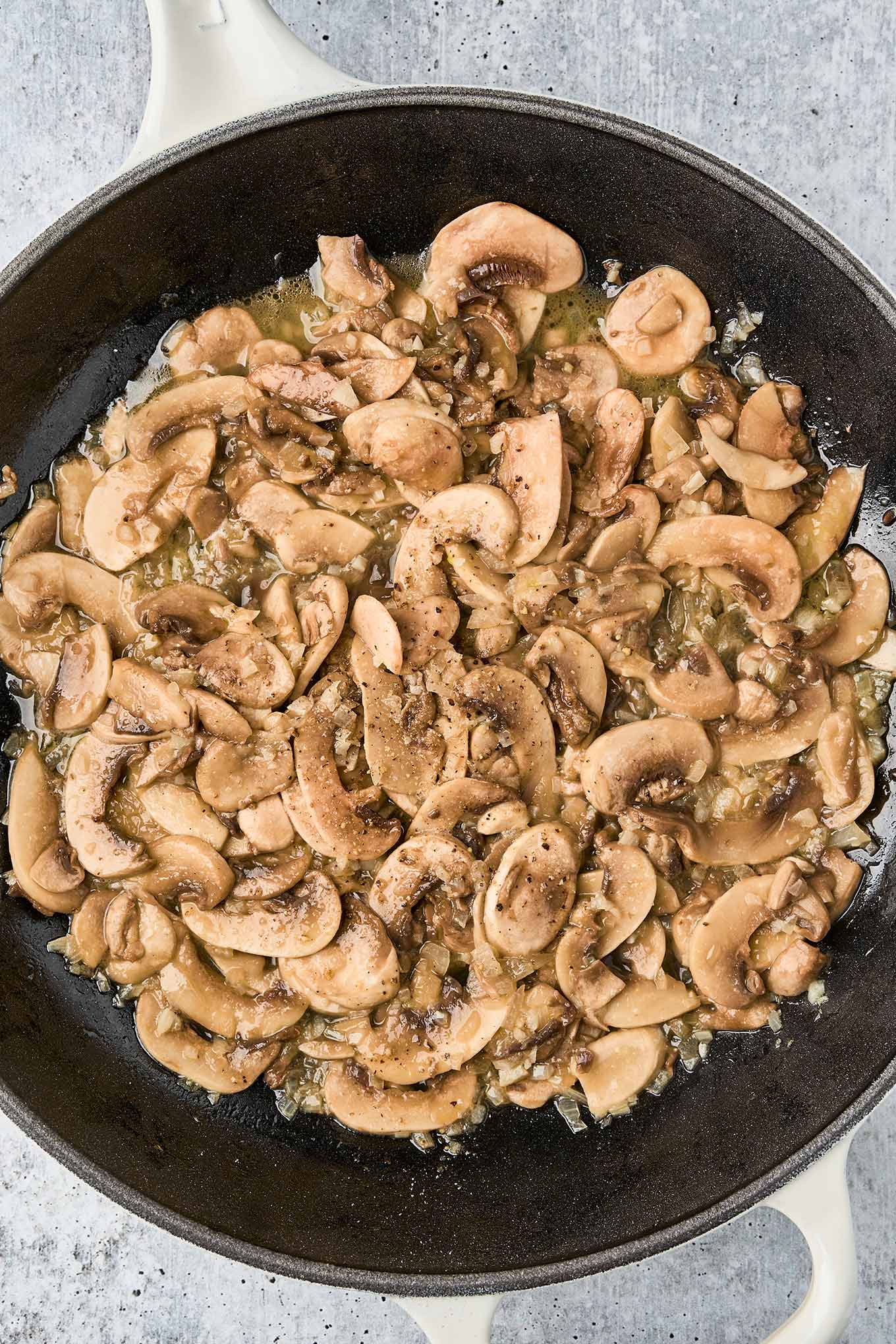 Sliced mushrooms saut&eacute;ing with garlic and shallot in a skillet for truffle mushroom pasta.