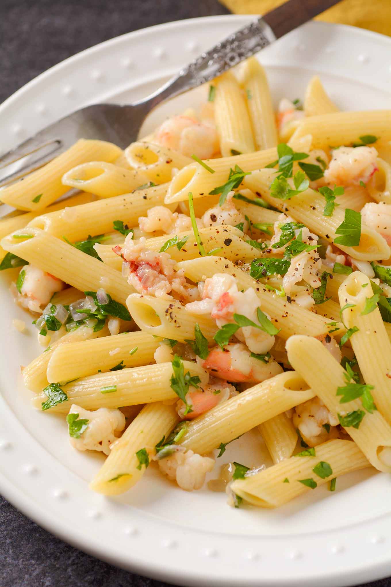 Lobster tail pasta with shallot butter, white wine, and truffle oil on a white plate with parsley garnish.