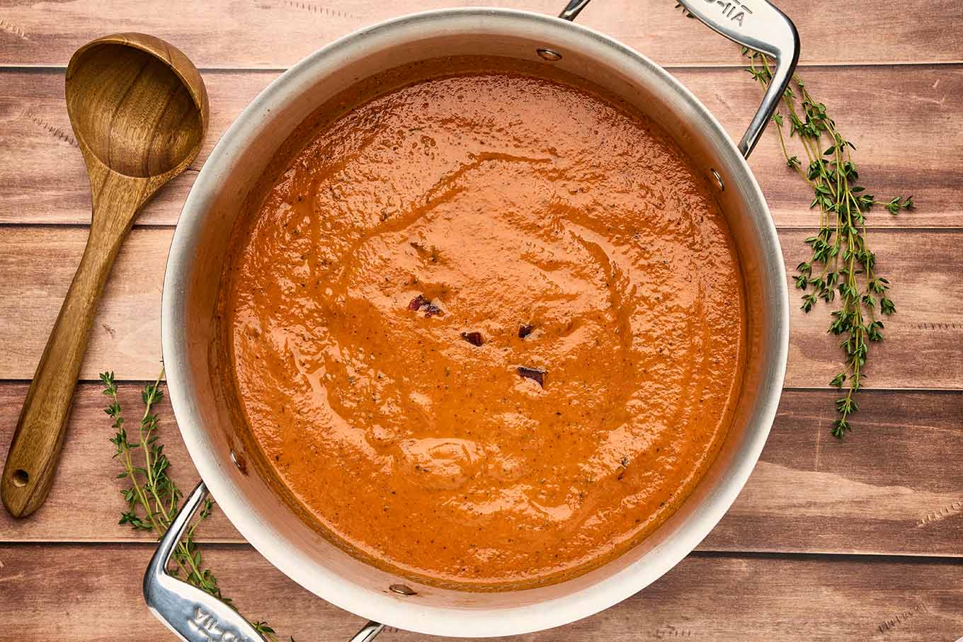 Fire-roasted tomato and bacon soup in a pot after blending, finished with bacon and a swirl of cream.