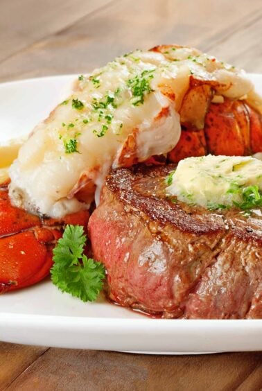 Surf and turf with pan-seared filet mignon, lobster tail, and shallot compound butter on a plate.