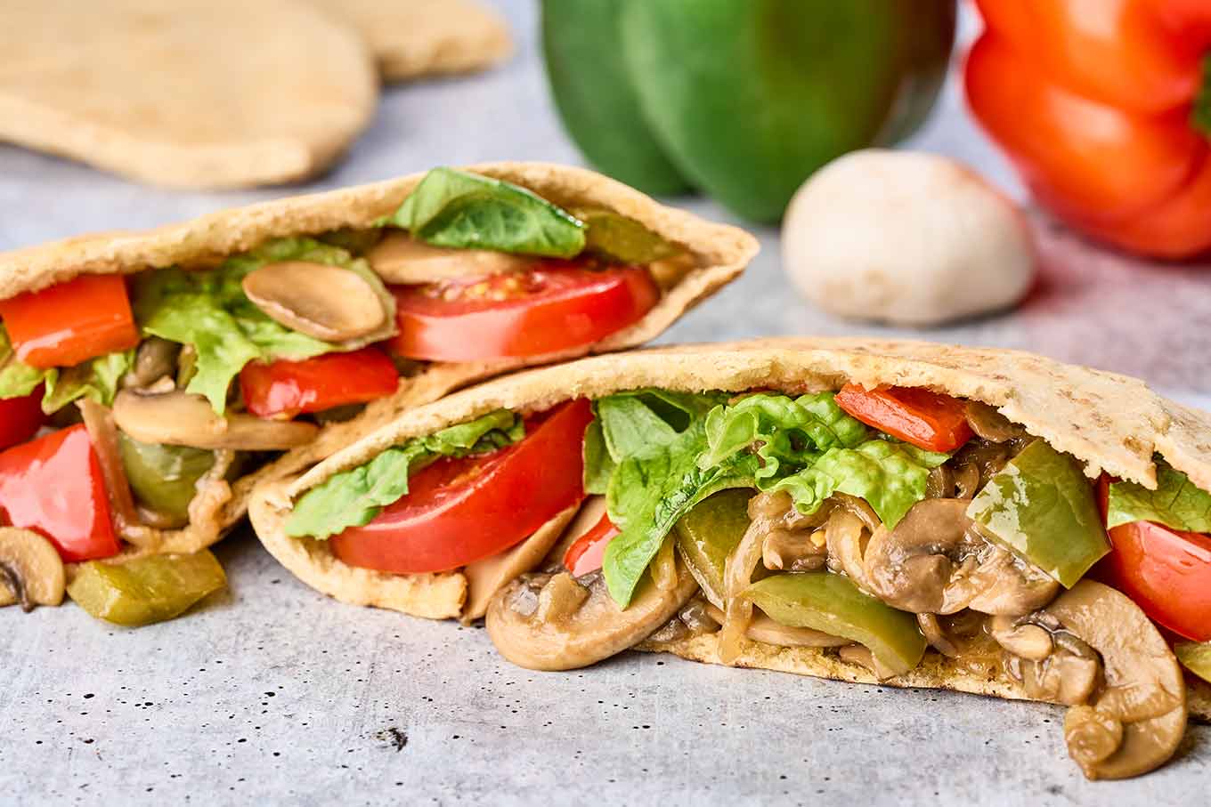 Vegetable pita melt sandwich with saut&eacute;ed mushrooms and peppers, layered with lettuce and tomato.