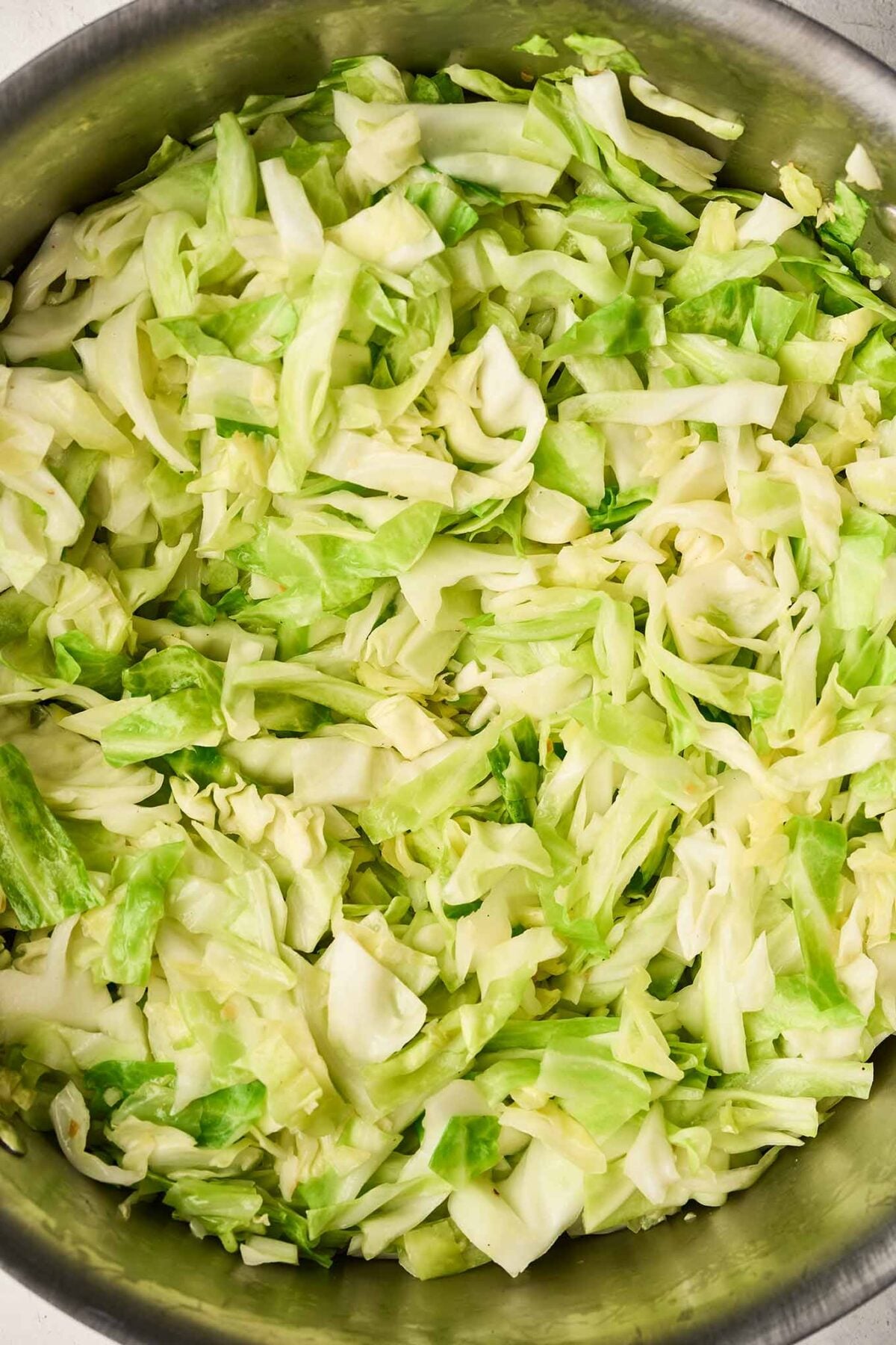 Cabbage sautéing with garlic in a soup pot before adding potatoes, broth, and seasonings.