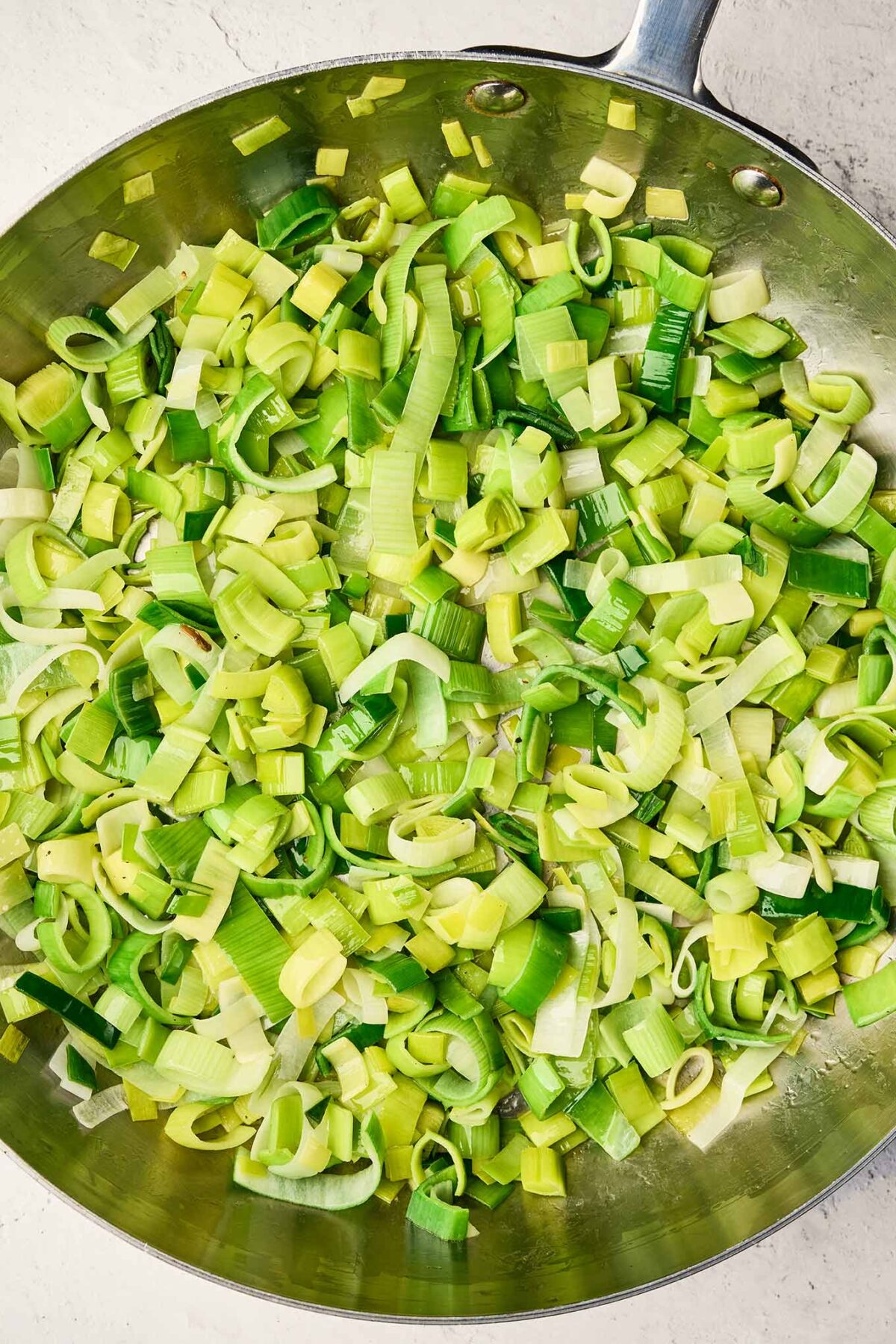 Sliced leeks cooking in butter until softened for cabbage leek potato soup.