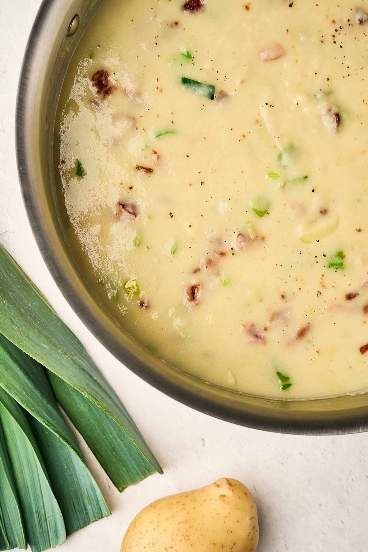Blended cabbage leek potato soup with sautéed leeks and bacon mixed in before serving.