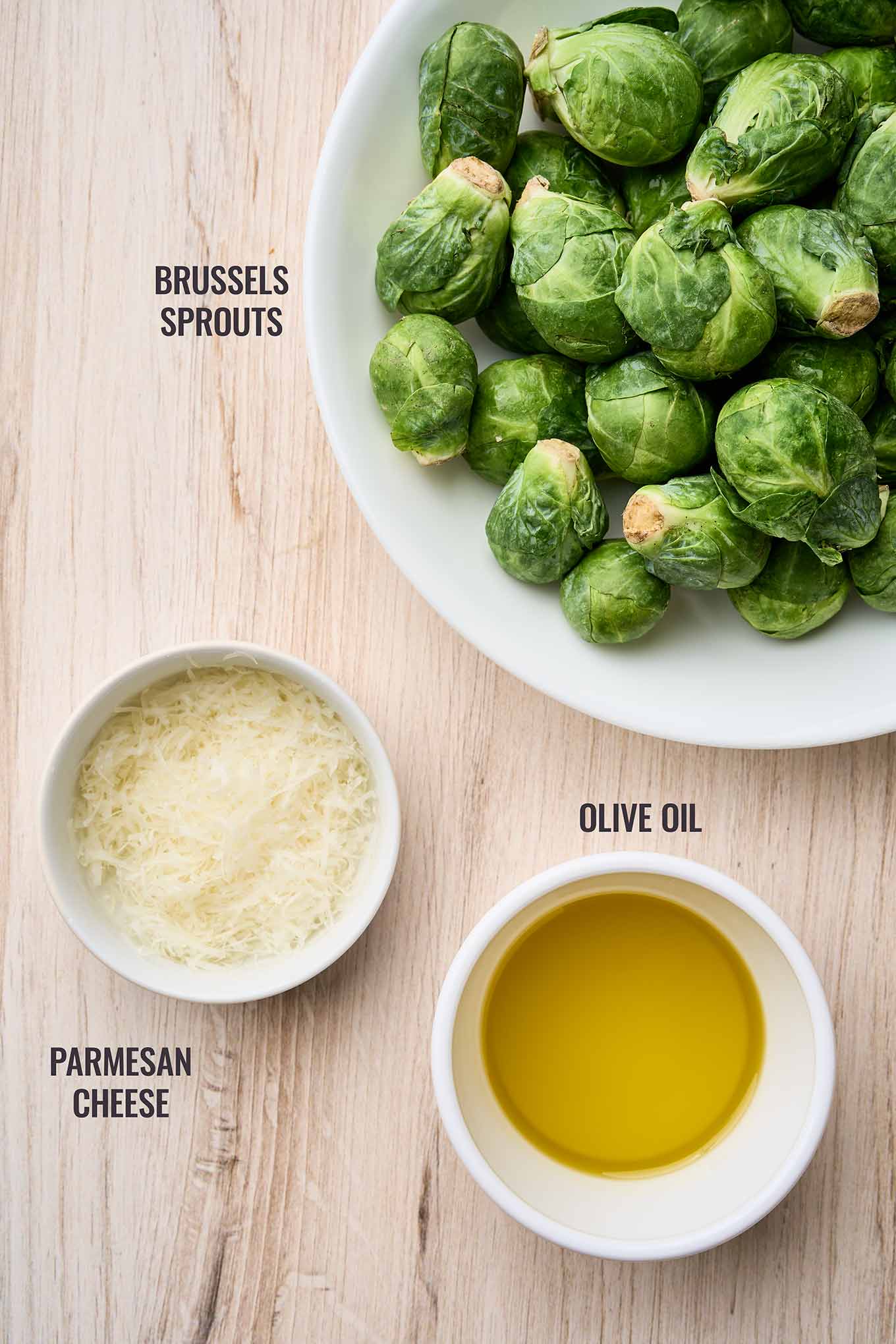 Ingredients for warm Brussels sprouts Caesar salad including fresh Brussels sprouts, olive oil, and grated Parmesan.