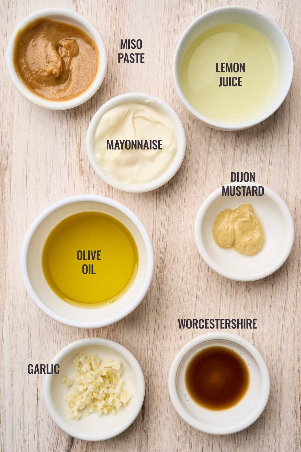 Ingredients for Caesar dressing for warm Brussels sprouts Caesar salad including miso paste, lemon juice, mayonnaise, Dijon mustard, garlic, and Worcestershire.