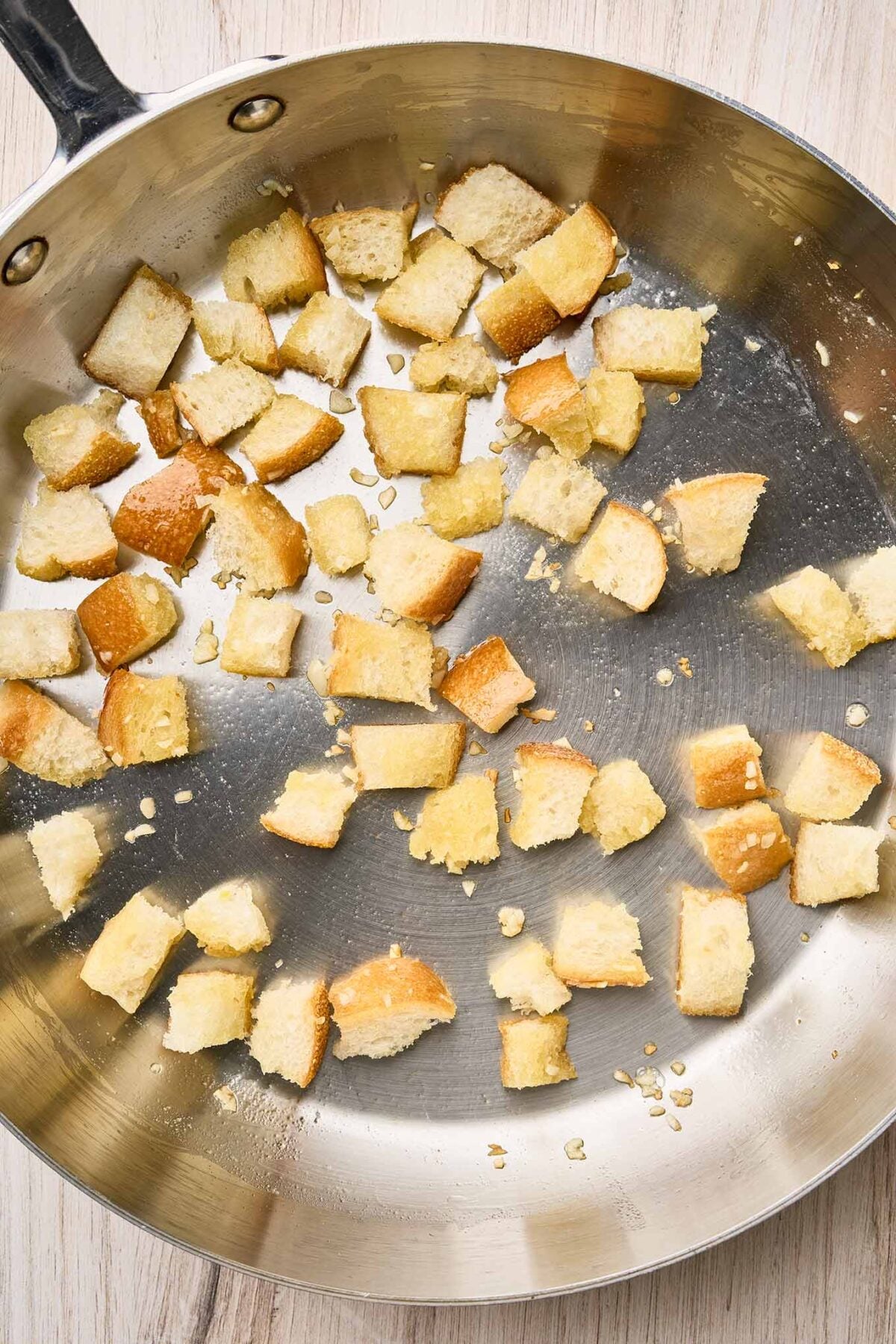 Bread cubes and minced garlic saut&eacute;ing in a skillet for homemade croutons.
