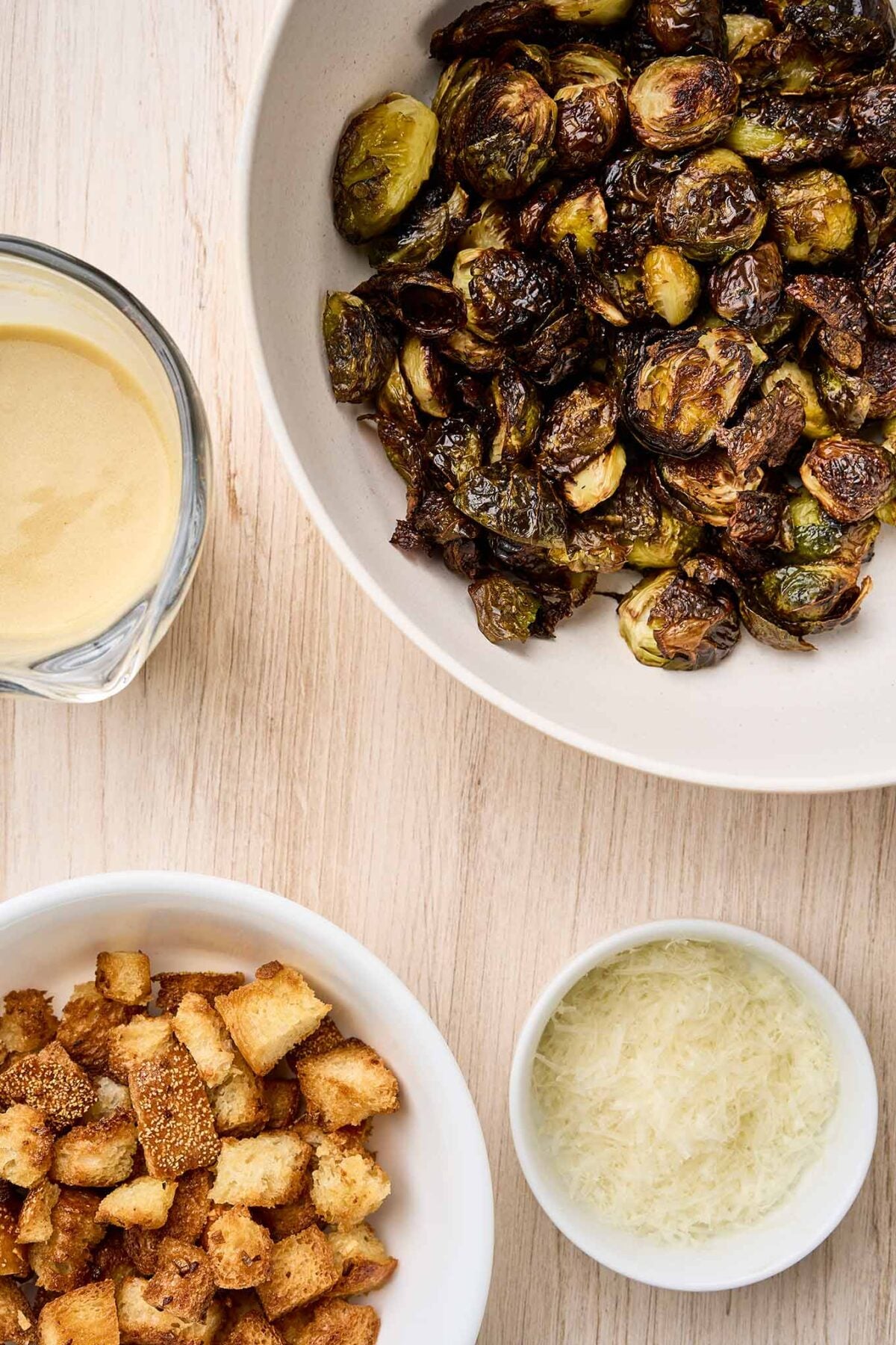 Roasted Brussels sprouts, toasted croutons, Caesar dressing, and grated Parmesan cheese ready to assemble.