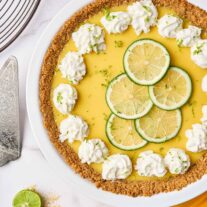 Florida Key lime pie with graham cracker crust, topped with whipped cream and lime slices in a white pie plate.